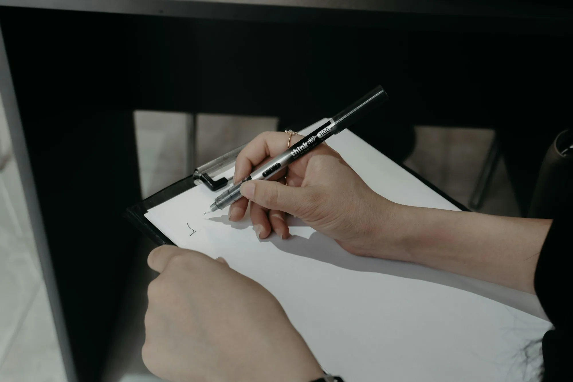 Hands writing on a clipboard with a pen, like a homeowner in Markham sorting out whether insurance covers solar panel removal for a roof claim